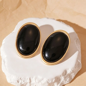 Detail of vintage oval resin earrings with gold edges on white stone base display