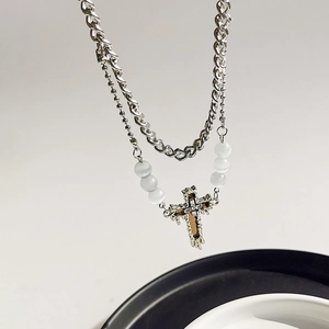Detailed close-up of double-layer silver cross necklace with metal chain and white beads