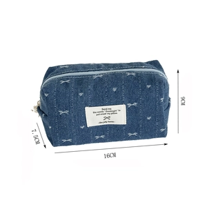 Detail of blue denim bow pouch showing size 16x9x7.5cm with embroidery and white label