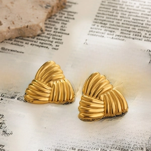 Detail view of gold triangle textured earrings placed on a vintage book page