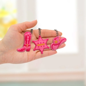 Pink PVC cowboy keychain set featuring boot, sheriff star, and hat charms with metal rings