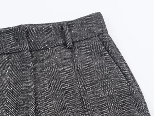 Detailed close-up of grey herringbone tweed fabric texture on suit trousers waist