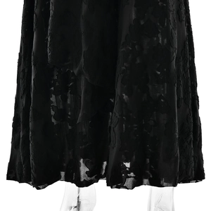 Detailed view of black jacquard fabric texture and draped hem on the elegant long dress