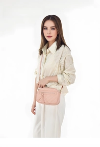 Pink quilted shoulder bag with gold chain strap shown on a model against white background