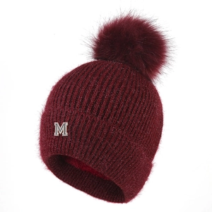 Berretto in maglia bordeaux con pompon di pelliccia e logo M in metallo su fondo bianco