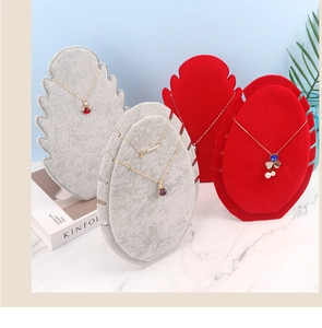 Gray and red velvet necklace display stands arranged on a marble surface in a studio setting