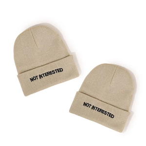 Beige knitted beanie with black NOT INTERESTED embroidery on folded cuff