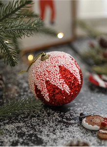 Gros plan d'une boule de Noël rouge scintillante avec effet neige et décor festif