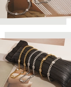 Detailed view of gold and silver Cuban chain necklaces with round zircon on a black cushion
