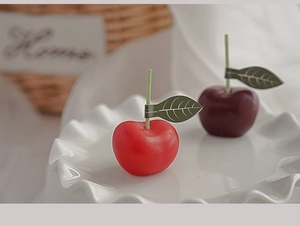 Primer plano de velas perfumadas con forma de cereza roja y púrpura sobre un plato