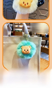 Close-up of plush bear keychains in white and teal with premium orange gift packaging