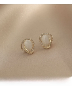 Close-up of oval opal stud earrings with shimmering gold finish and zircon halo