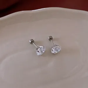 Minimalist round cubic zirconia stud earrings in silver prong setting on ceramic tray