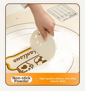 Detail showing a person using a white silicone scraper on a non-stick kneading mat