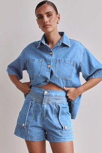 Detail eines blauen Denim-Zweiteilers mit Kurzarmhemd und doppelten Brusttaschen am Set