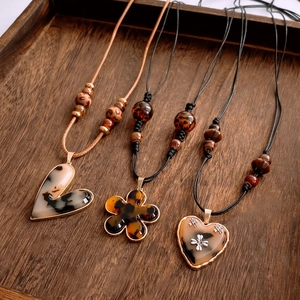 Close-up of leopard resin flower heart pendants with woven cord on vintage wooden tray