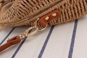 Detailed close-up of straw woven texture and brown leather strap with gold metal buckle