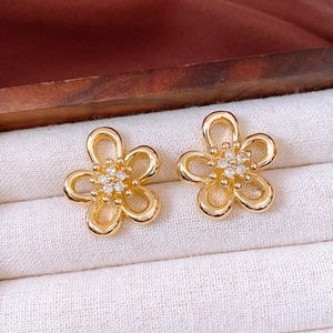 Detail of gold flower earrings with white zircon centers in a jewelry box setting
