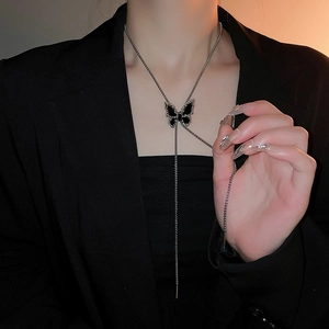 Dark style butterfly pendant necklace with crystal accents on an elegant model's neck
