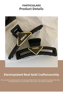 Detail of matte black shark hair clips with gold POWER triangle plate and real gold plating