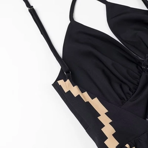 Dettaglio di un vestito nero con scollo a V profondo e motivi geometrici color kaki