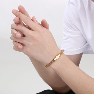 Close-up of golden cable wire bracelet with rectangular charm on model's wrist
