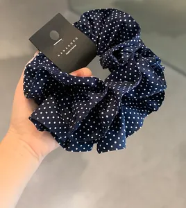 Nahaufnahme von marineblauem, doppellagigem Polka-Dot-Haargummi mit Rüschenkanten