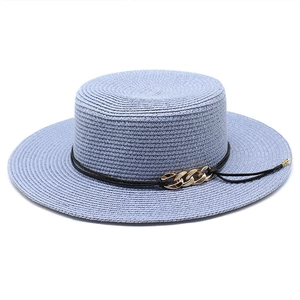 Détail d'un chapeau de paille bleu avec texture en spirale et boucle de chaîne dorée