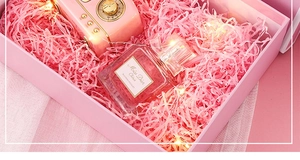 Close-up of a pink bow gift box featuring shredded paper and decorative warm LED string lights