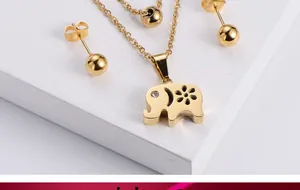 Macro detail of gold elephant pendant necklace and ball stud earrings jewelry set