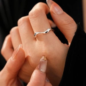 Detailed close-up of a minimalist silver wavy irregular ring on a model's finger