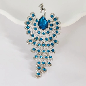 Detail of peacock brooch featuring blue crystals and teardrop gemstone on silver alloy