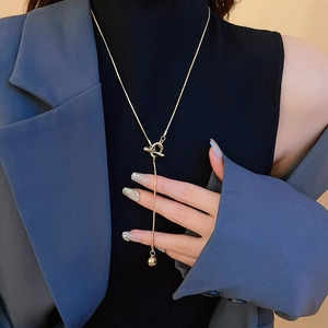 Detail shot of a minimalist gold Y-shaped necklace with round bead pendant worn by a model
