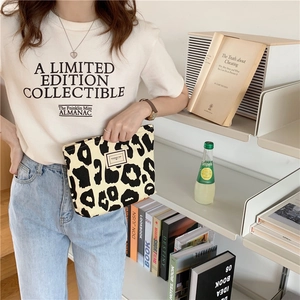 Close-up of leopard print canvas tote bag featuring a black zipper and woven brand label