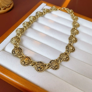 Détail d'un collier vintage à maillons tête de lion dorés sur plateau blanc