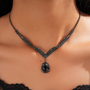 Macro shot of a black drop pendant necklace with intricate crystals on a model's neck