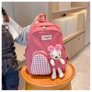 Detail of pink kids backpack with plush bunny doll and red checkered front pocket