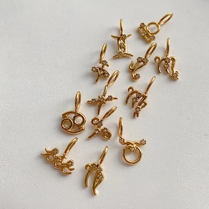 Detalle macro de 12 colgantes del zodiaco bañados en oro con brillantes de cristal