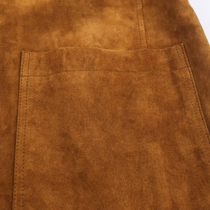 Détail de veste en daim marron caramel montrant la poche à double couture et la texture