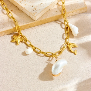 Gold ocean necklace with starfish and shell pendants on a neutral stone background