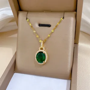 Gros plan d'un collier goutte d'or avec zircon émeraude dans une boîte à bijoux