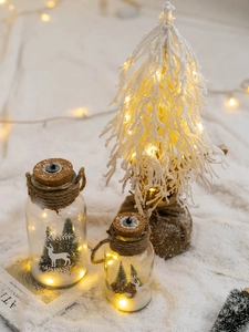 Macro detail of LED glowing glass jars with reindeer scene on snowy Christmas background