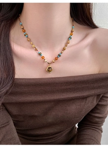 Détail d'un collier de perles bohème avec touches d'ambre et un pendentif en métal doré