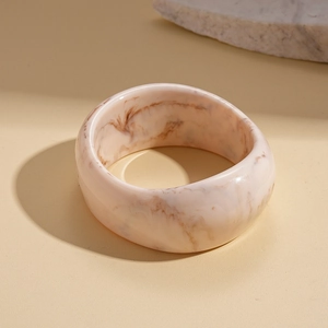 Detail shot of thick resin bangle featuring pink marble texture and smooth finish