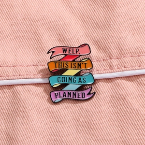 Rainbow ribbon enamel pin with Welp This Isnt Going As Planned quote on pink denim background