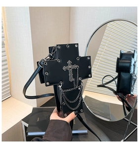 Detail of gothic cross bag featuring silver chains and metal rivets on black leather surface