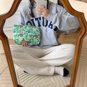 Close-up of green floral cotton makeup bag with white flower pattern and brand label