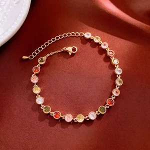 Bracelet tennis plaqué or avec zircons colorés sur un fond en tissu de soie rouge foncé