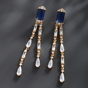 Close-up of geometric blue zircon earrings with gold plating and sparkling stone details