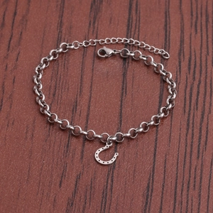 Silver titanium horseshoe pendant bracelet on minimalist steel chain over wood surface